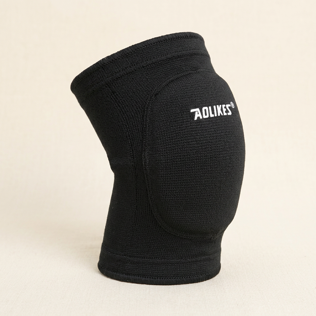Black padded knee sleeve shown without a model, highlighting its rounded front cushioning and knit cuffs on ivory.