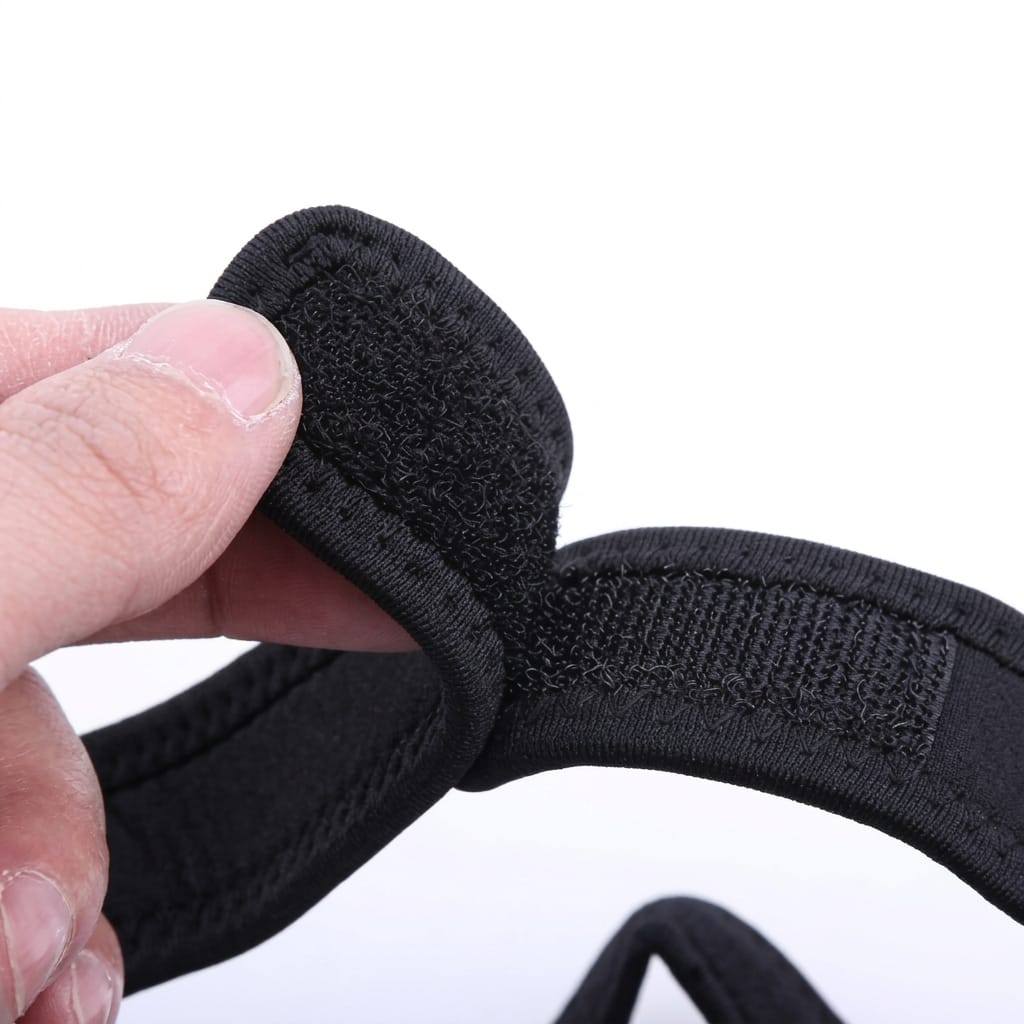 Close-up of a black stretch fabric chin support wrap with hook-and-loop fastening, held by a hand against a plain white background.