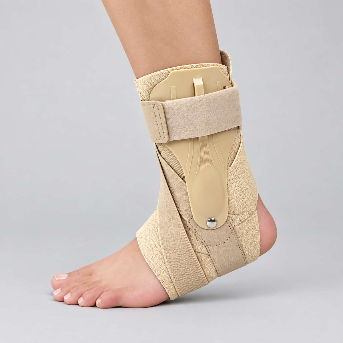An adjustable cross strap ankle brace shown on a person's foot against a light gray studio background.