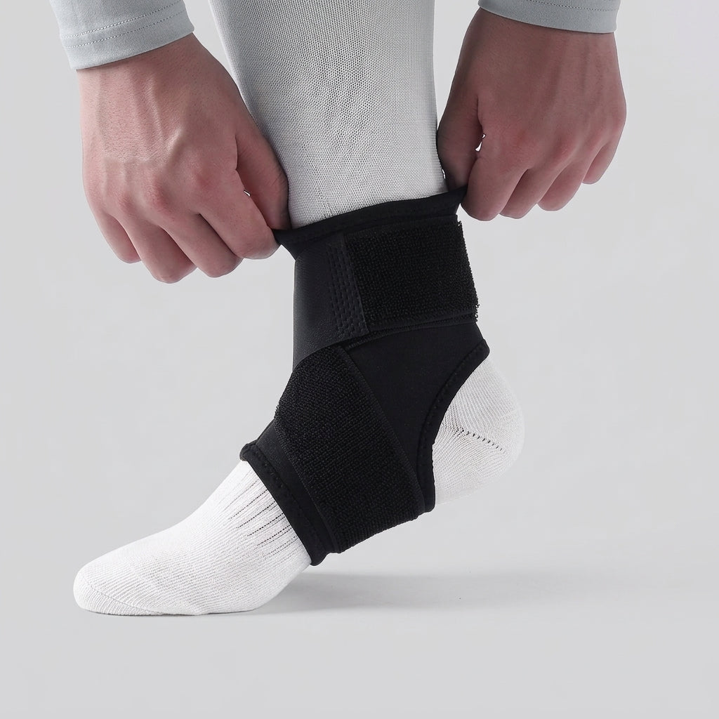 A person wearing a black kids ankle support brace over a white sock, with both hands adjusting the top strap. The background is a clean, light gray studio backdrop.