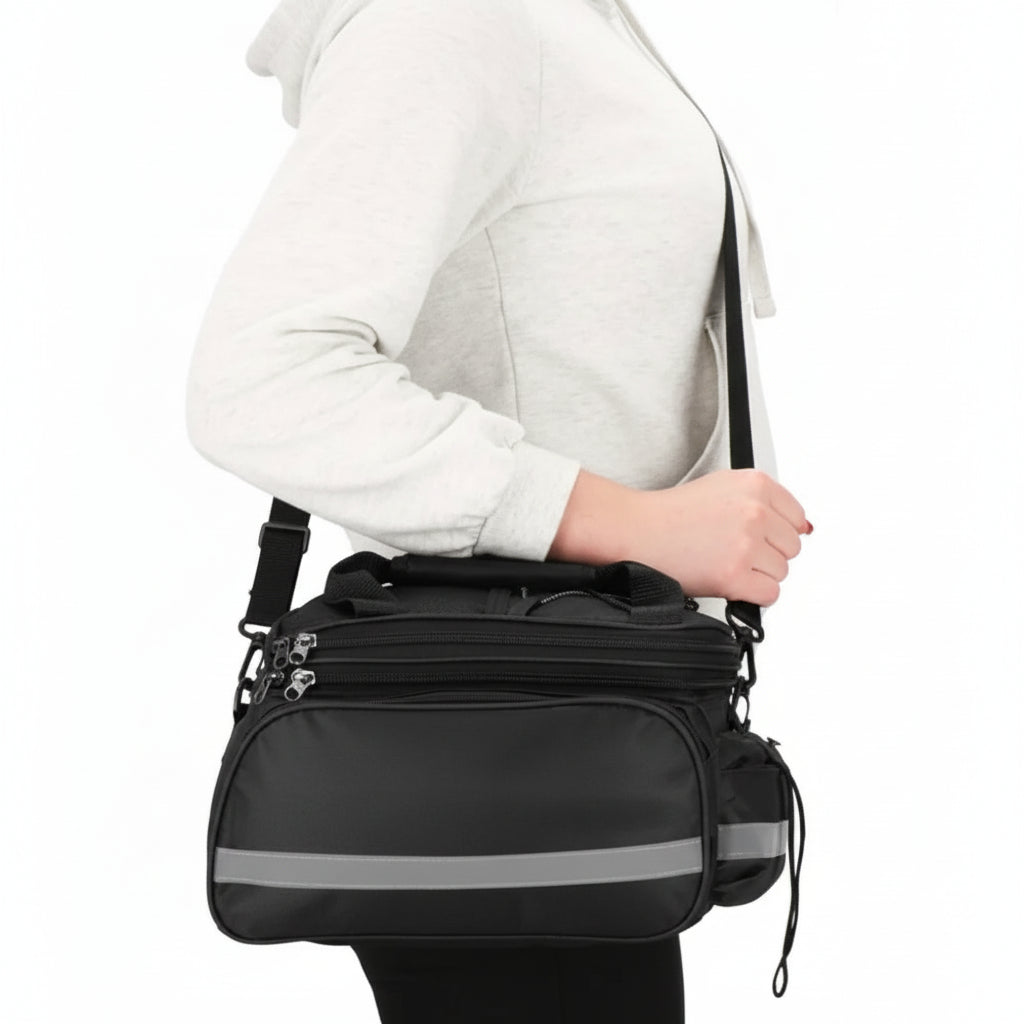A black bicycle bag shoulder carry with a reflective gray stripe, worn by a person in a light gray hoodie against a white background.