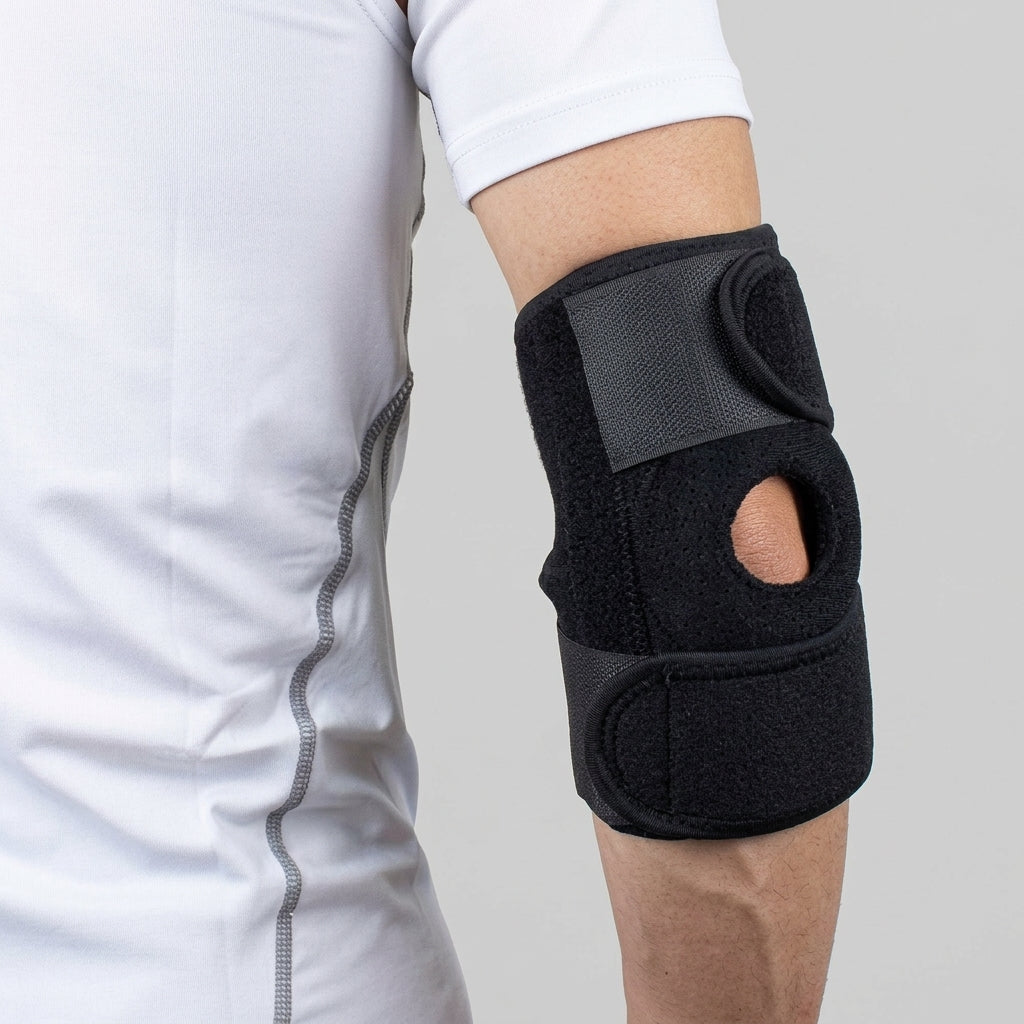 A black elbow brace arthritis joint pain worn on a person's elbow, shown against a light gray background with the person wearing a white athletic shirt.