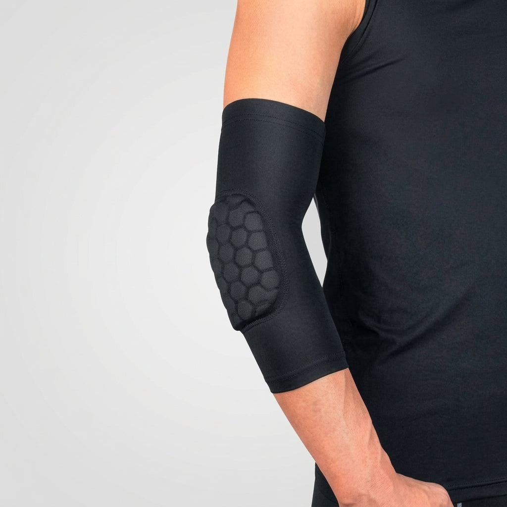 A close-up of a person wearing a black elbow pads for kids sports with a raised honeycomb-textured protective pad on the forearm, paired with a black tank top against a light gray studio background.