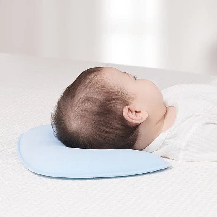 A newborn baby sleeping peacefully on a hypoallergenic ergonomic head support pillow in a crib.