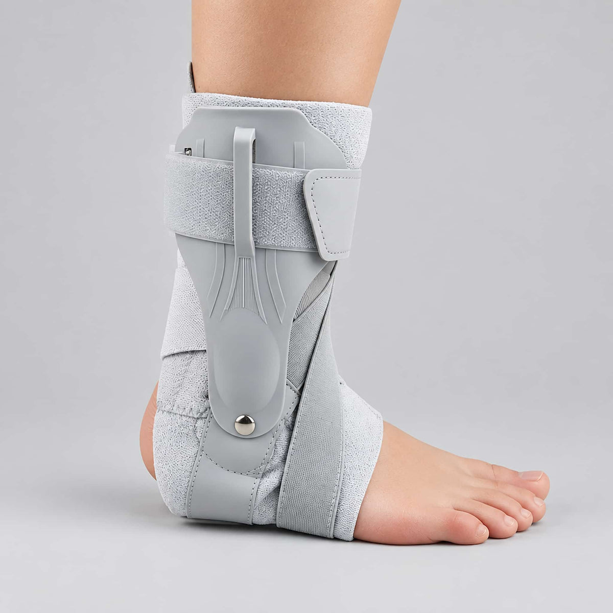 A figure 8 ankle support strap worn on a person's ankle, shown against a plain light gray studio background. The brace has multiple straps and molded support panels, with part of the foot and lower leg visible.