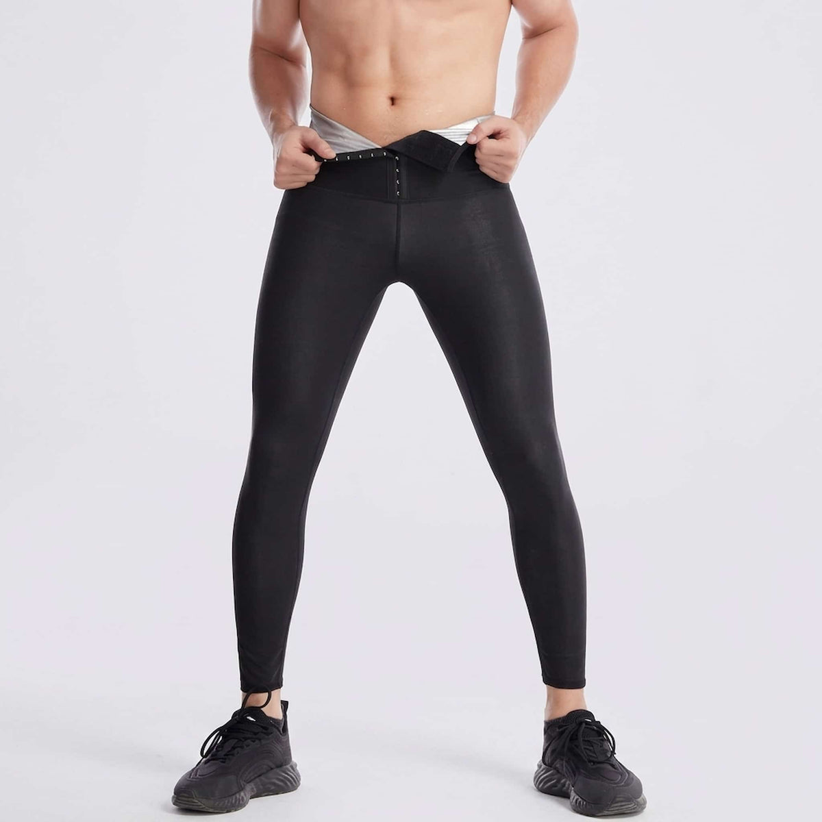 A man wearing front hook sauna leggings, shown against a plain light gray studio background.
