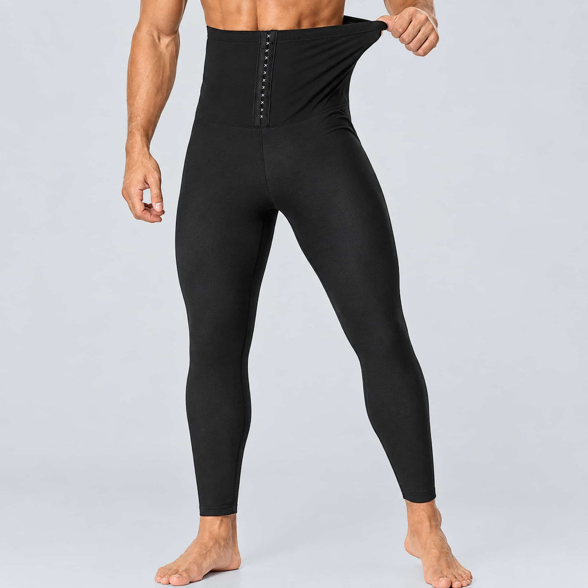 A man wearing high waist sauna leggings against a light gray studio background.