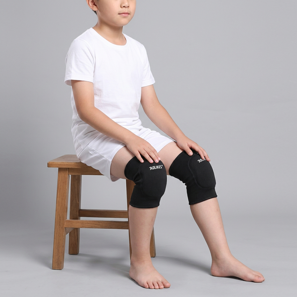Child seated sideways on a stool wearing black child knee pad sleeves with rounded front cushions.