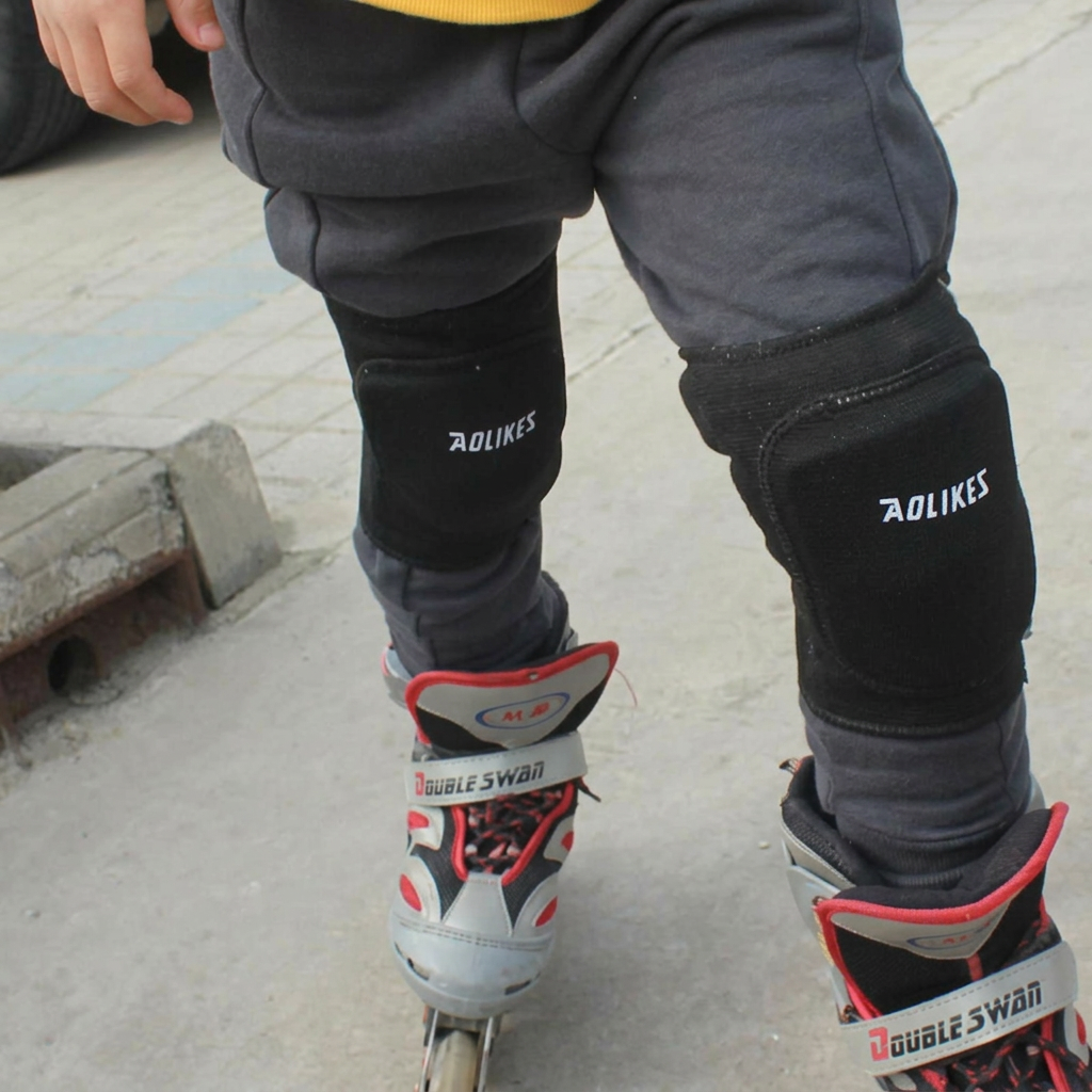 Black padded knee sleeves worn over gray pants with gray and red inline skates on pavement.