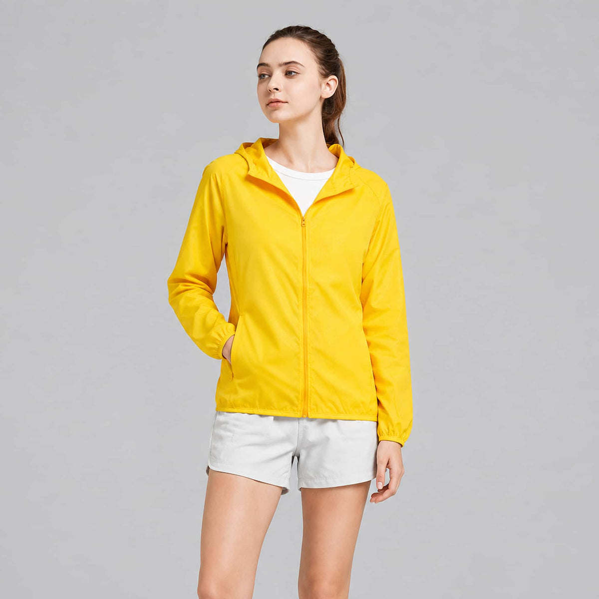 A woman modeling a lightweight packable rain jacket, photographed against a plain light gray studio background.