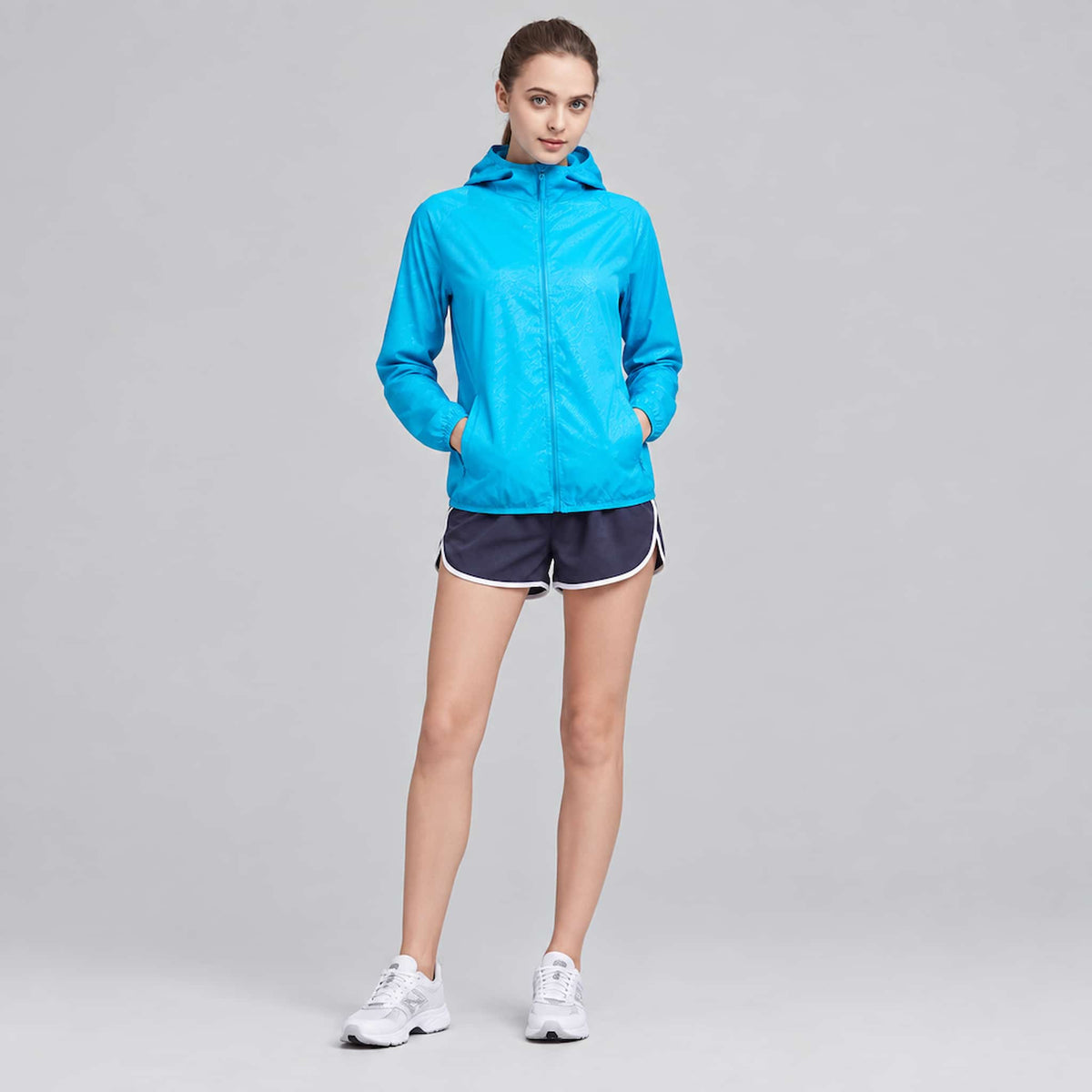 A woman modeling a lightweight sun protection jacket, against a solid light gray studio background.