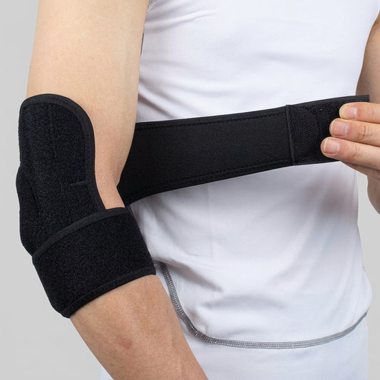 A black medial epicondylitis brace being adjusted around a person's bent elbow, worn over a white sleeveless top against a light gray background.