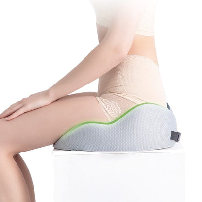 A model sitting comfortably at a desk using a orthopedic tailbone pillow on their chair.
