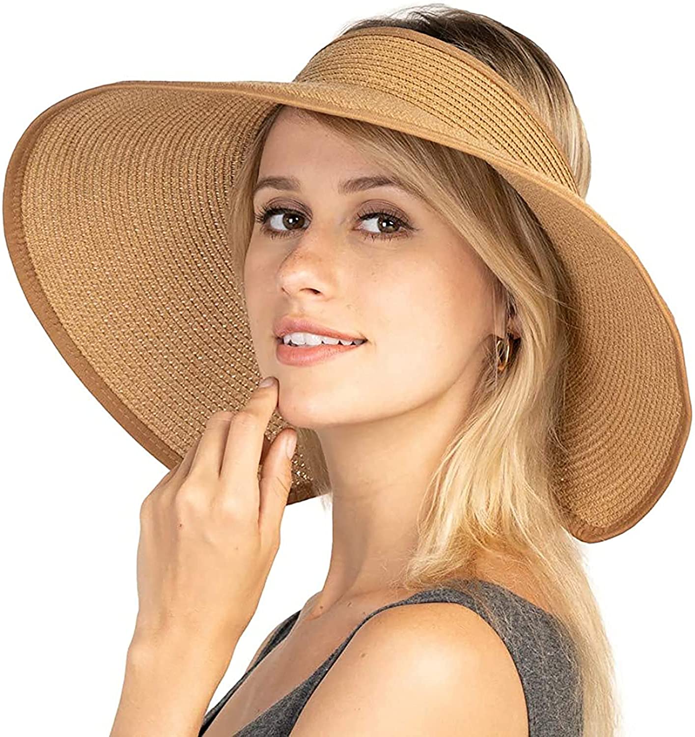 A model wearing a beige packable vacation sun hat while relaxing on a sunny beach.