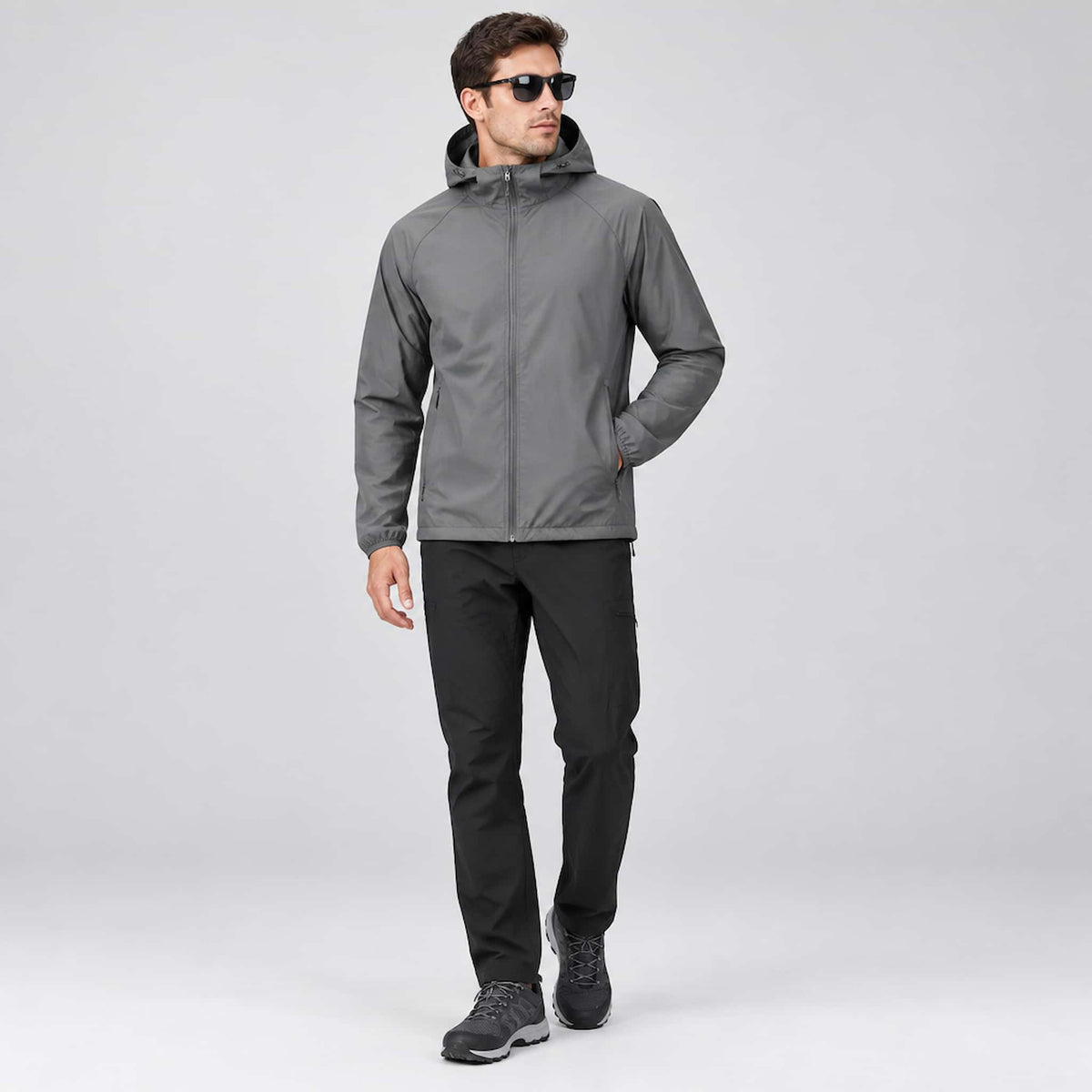 A man wearing a sun protection jacket for outdoor activities stands against a light gray studio background.