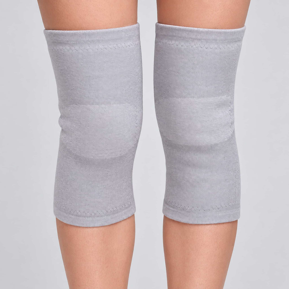 A pair of thickened plush knee warmers worn on a person's legs, shown against a plain light gray studio background.