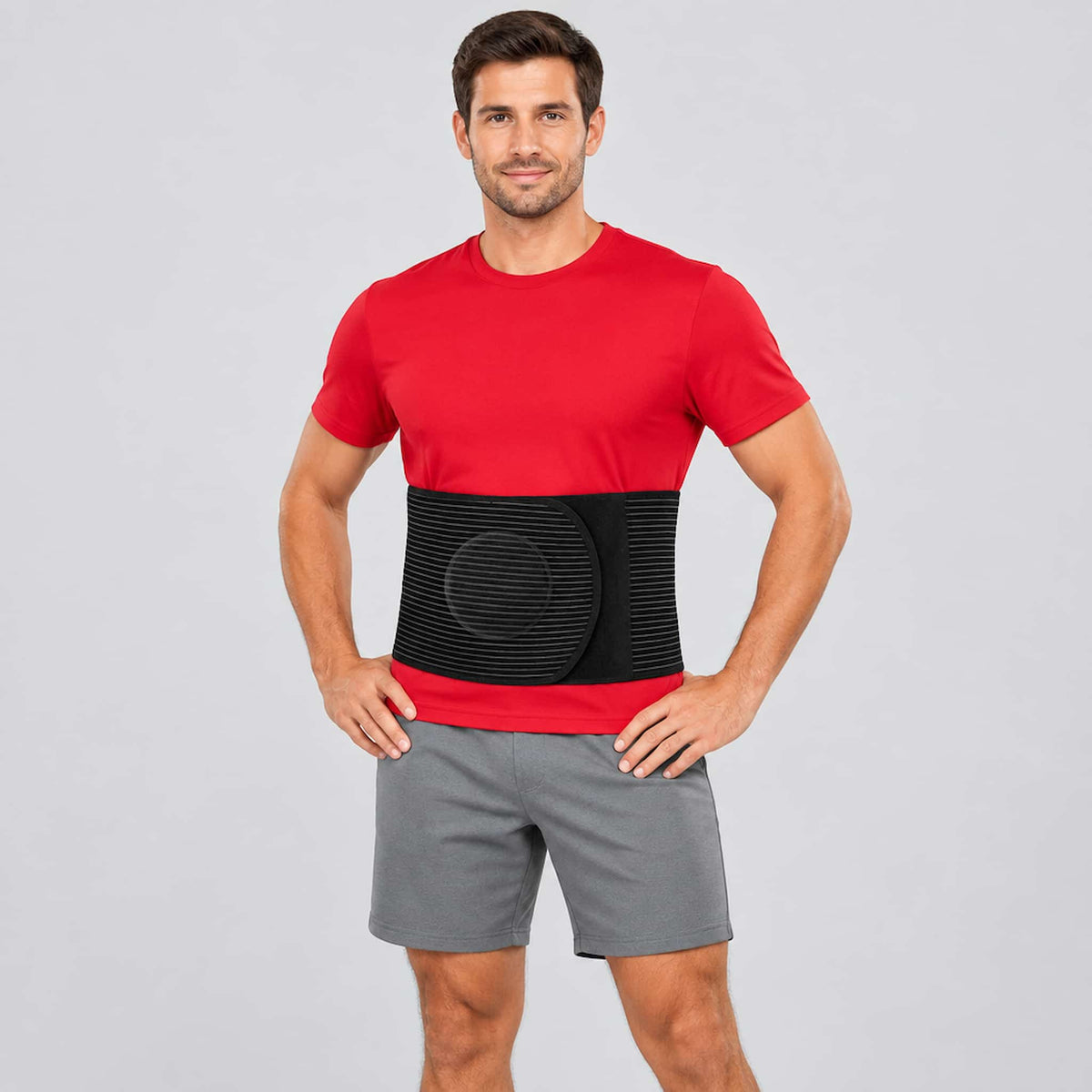 A man modeling an umbilical hernia support belt, standing against a light gray studio background.